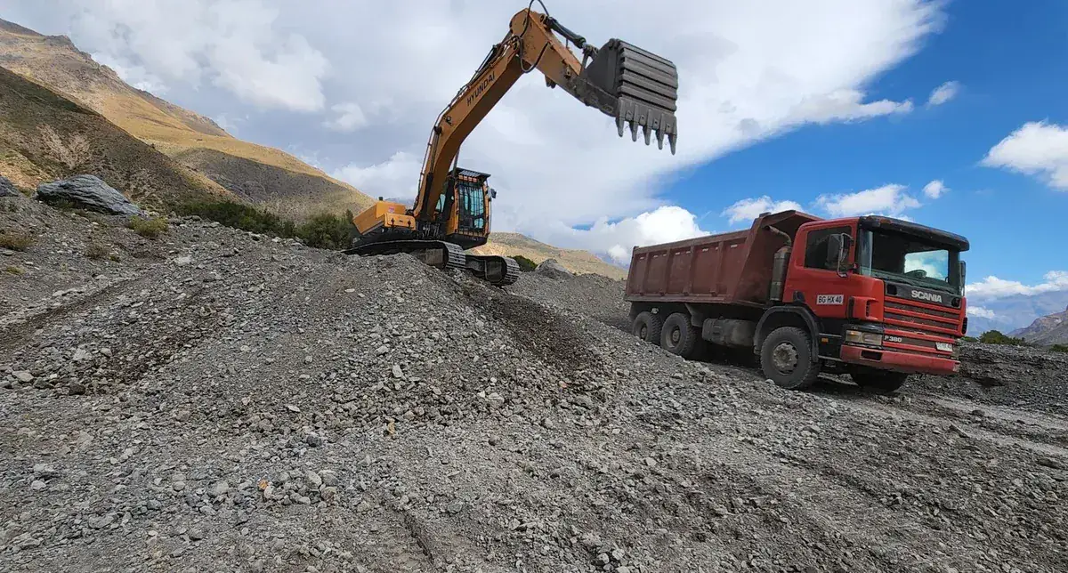 Excavadora cargando camión tolva en faena de cordillera — AL2 Construcciones
